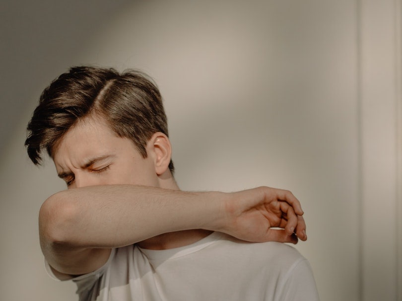 a sick man covering his mouth while coughing