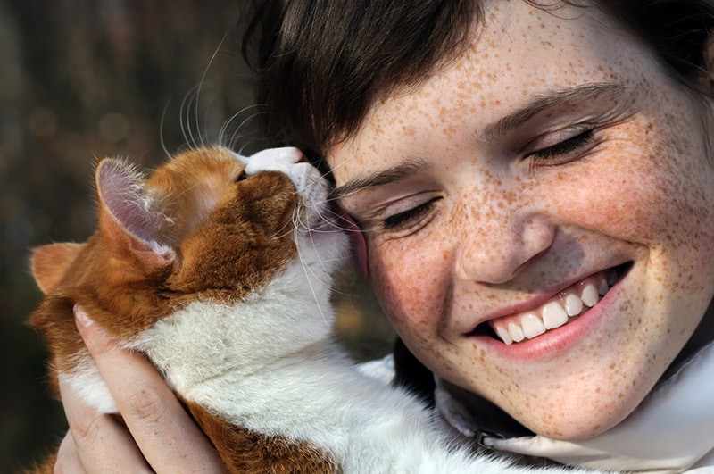 cat licking the girl's hair